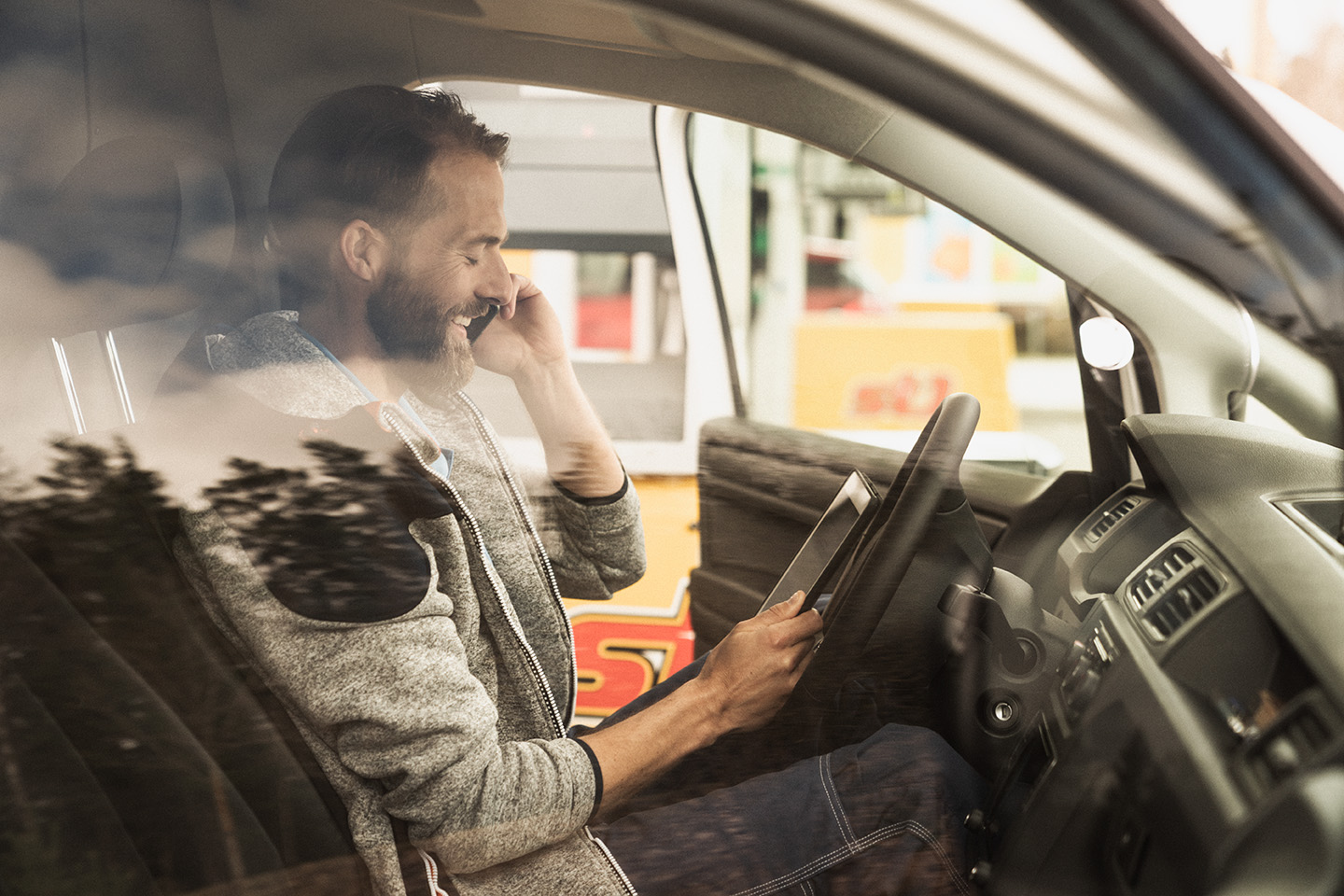 Man sitter i bil med mobiltelefon i handen